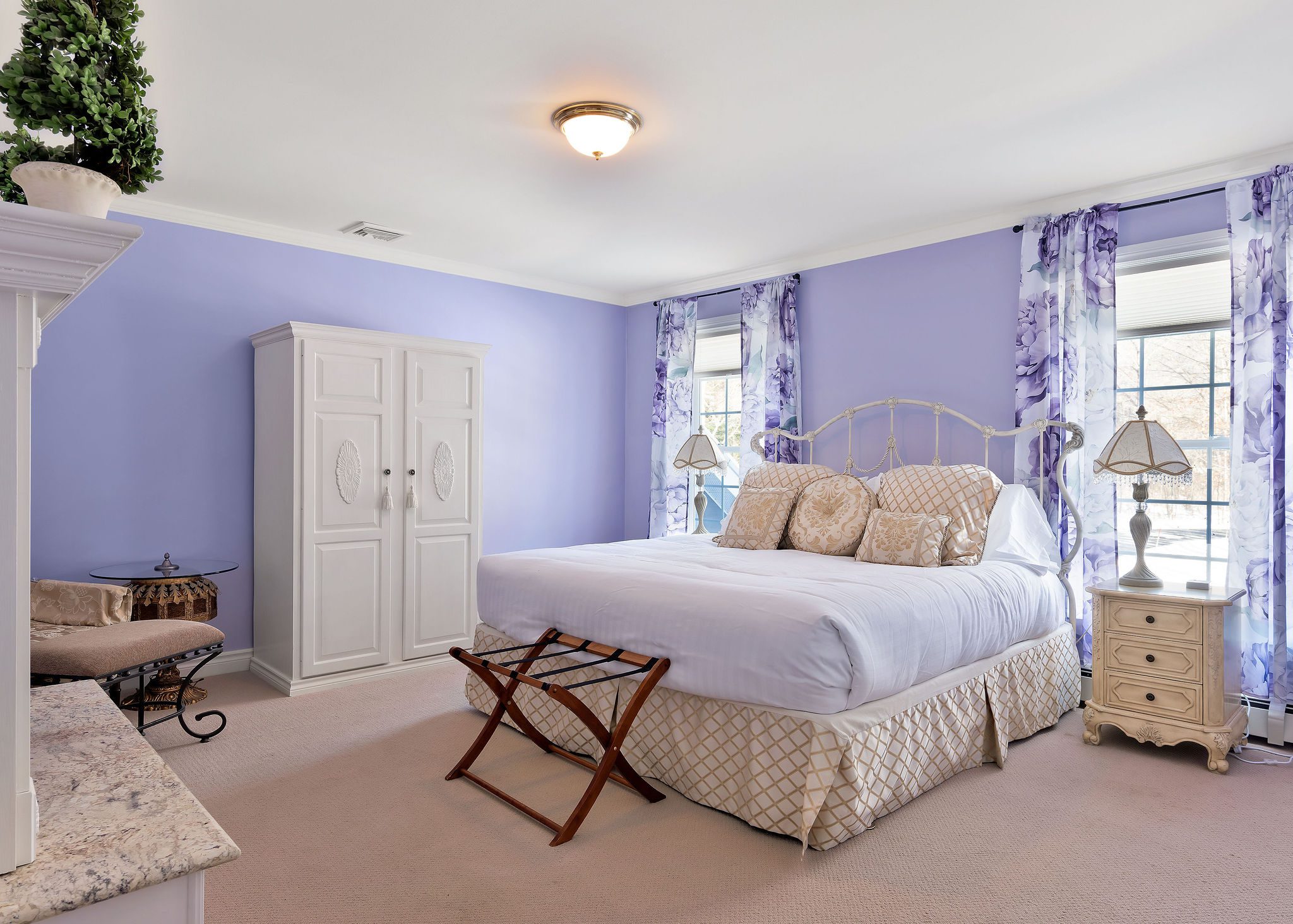 Cozy bedroom with lavender walls, a white bed, and matching wardrobe.