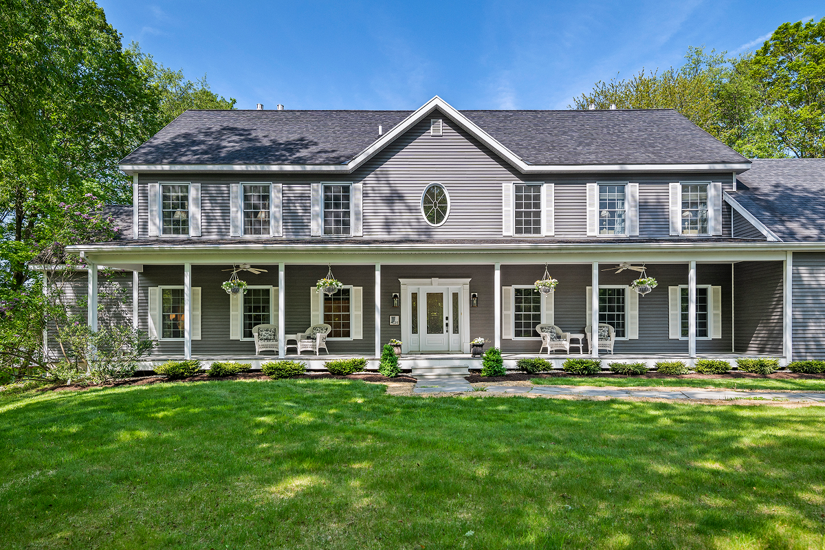 Large two-story gray house with white trim and a spacious front lawn.
