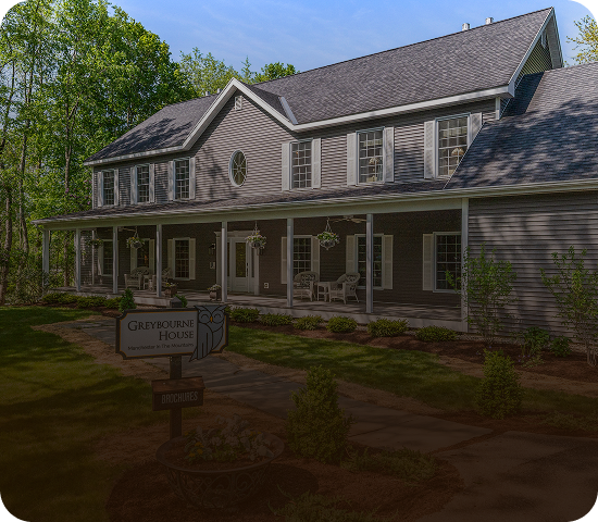 Historic two-story building with a large porch and multiple windows.