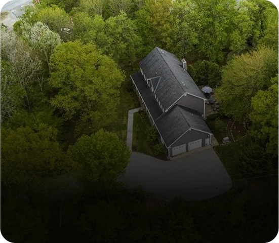 A house surrounded by dense green trees viewed from above.